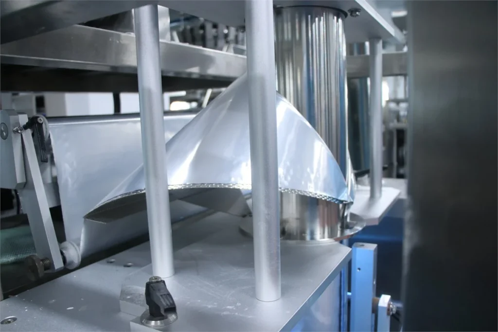 Forming collar and vertical tube on a ShengWei collar-type powder machine, where film wraps the tube before sealing