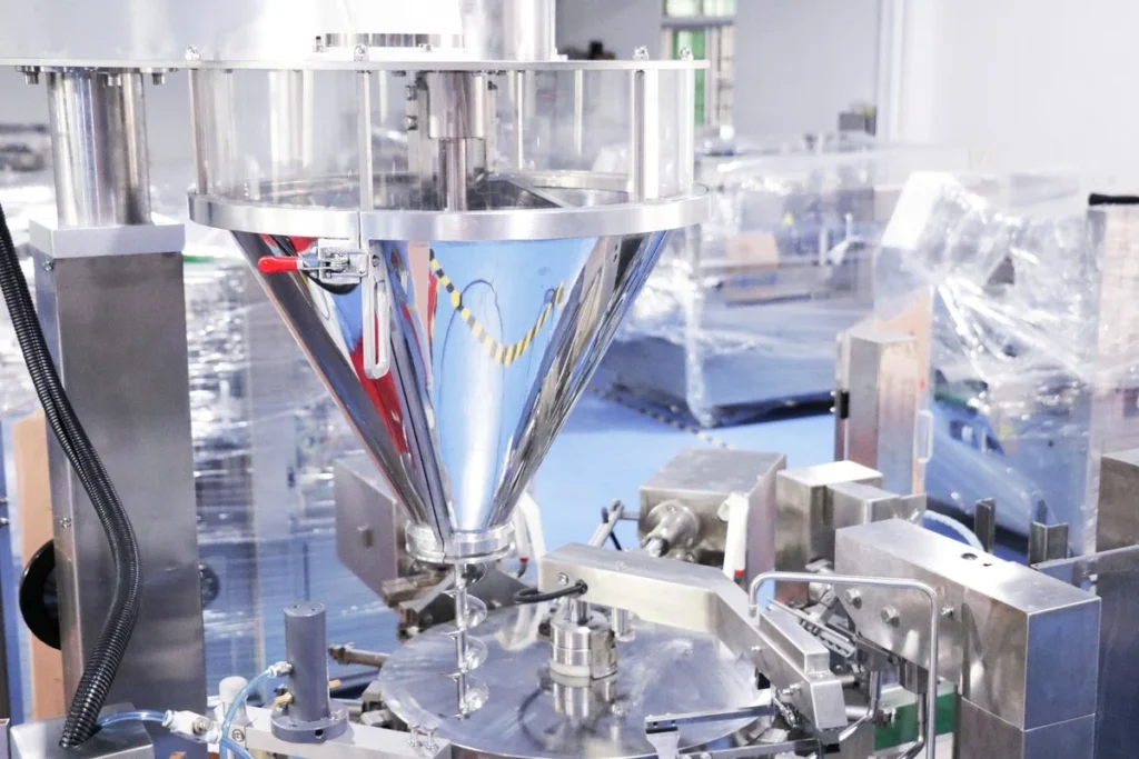 Stainless steel powder hopper with a built-in rotating agitator feeding a screw filler on a ShengWei premade-bag machine