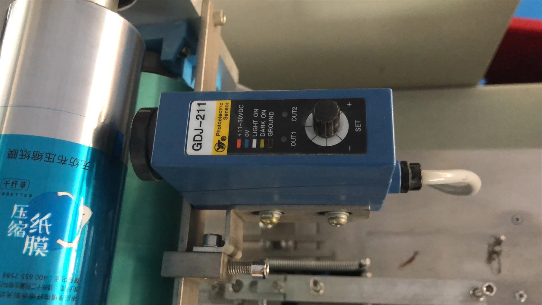 Photoelectric sensor mounted near the film path for eye mark registration on candy pillow packing machine
