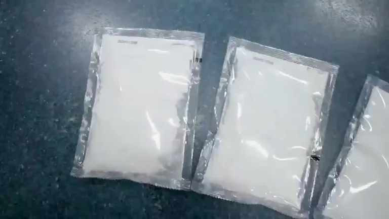 Clear unprinted sachets filled with white powder on a dark surface