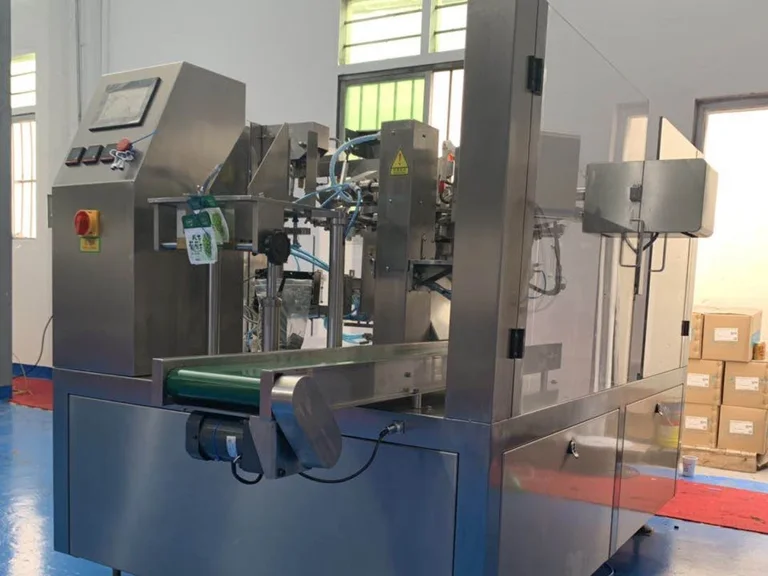 Eight-station premade pouch machine with a touch screen, an output conveyor and safety guards on a workshop floor