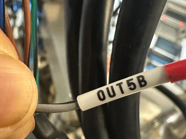 Close-up of a grey signal cable with a white marker sleeve printed OUT5B