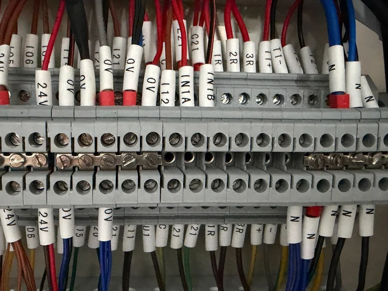 DIN-rail terminal strip in a control cabinet with every wire marked, including 24V, 0V, IN1A and IN1B