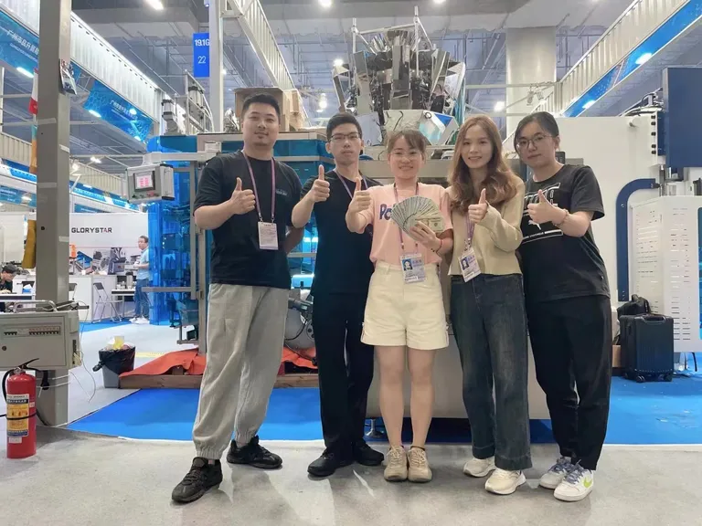 Stand H18.1 G22 de ShengWei Machine en la Canton Fair 2023 — el equipo frente a una envasadora vertical y una pesadora multicabezal